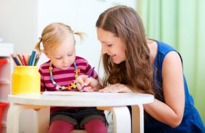 Young mother and her little daughter drawing together