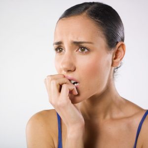 Portrait of a pretty young woman biting her fingers like she is stressed.